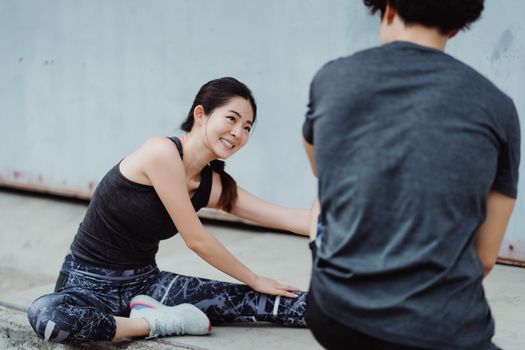 一位年轻的亚洲女子在户外健身课上伸展身体，面带微笑