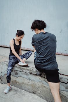 Two young adults stretching outdoors, preparing for a fitness session.