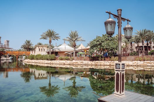 Scenic view of traditional architecture, palm trees, and a serene lake in a Dubai resort.