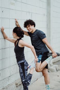 Energetic young couple stretching against a wall, embracing a healthy lifestyle.