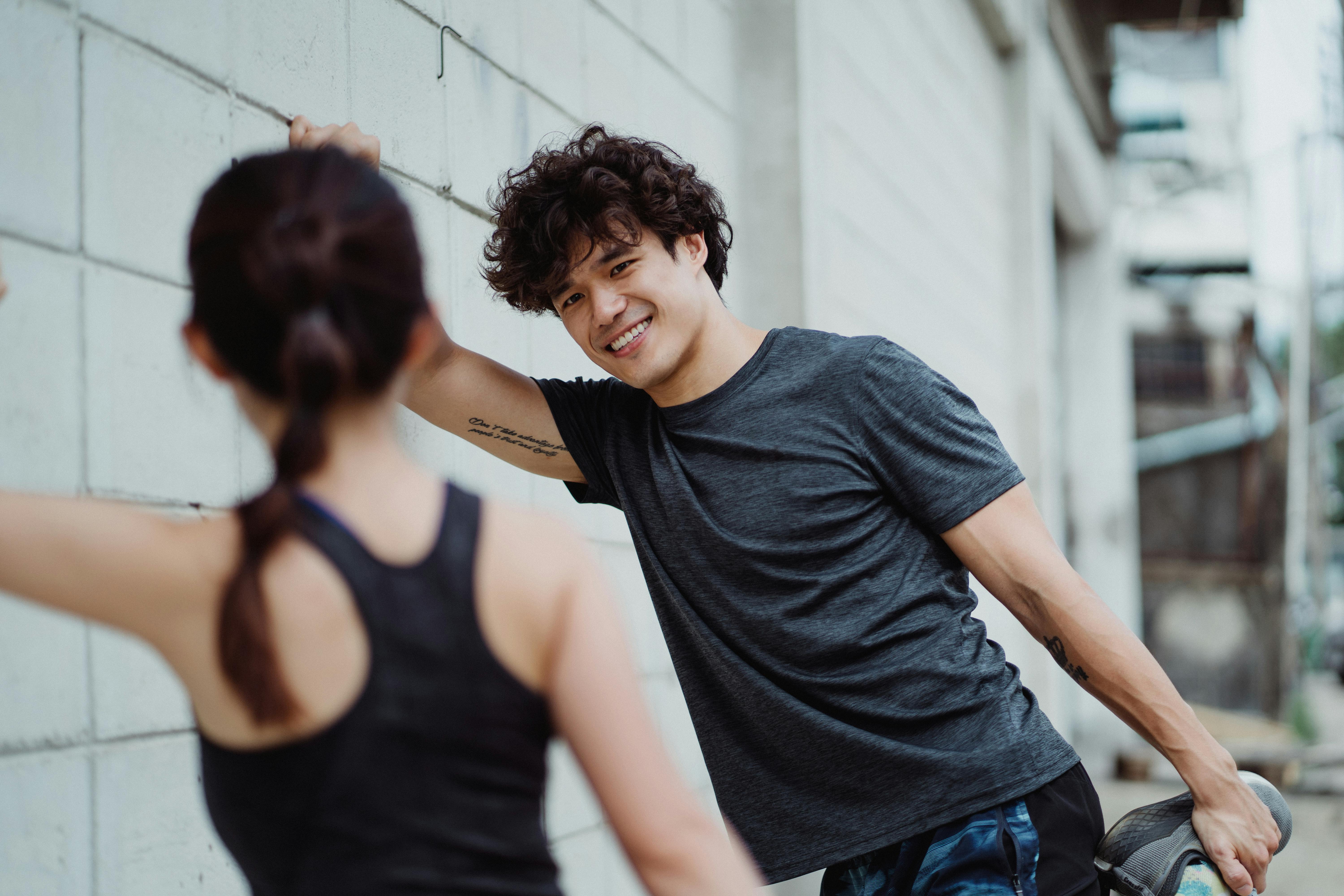 Young adults engaging in stretching exercises against a wall outdoors.