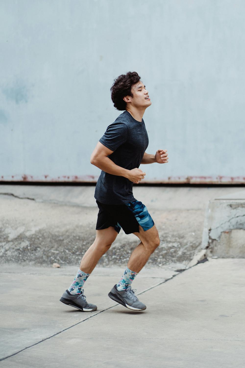 Man in Black T-shirt and Blue Shorts Running on Gray Concrete Road ...