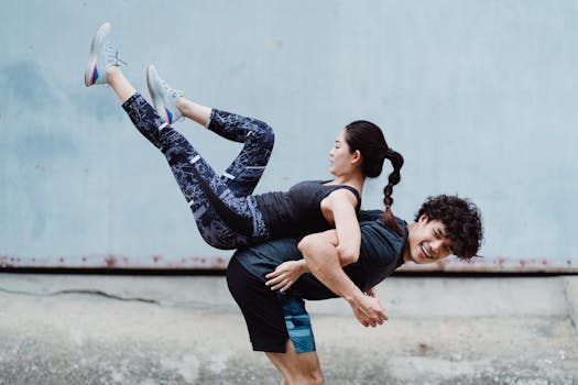 Energetic couple performing outdoor fitness routine showcasing strength and coordination.