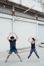 一对男女在户外建筑物旁进行跳跃表演，重点展示健身动作