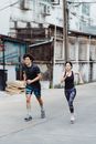 一对穿着运动服的夫妇在城市中一起慢跑，以此促进健身和户外活动