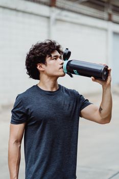 一名年轻人在户外用扳手补水，展现了健身与补水的结合