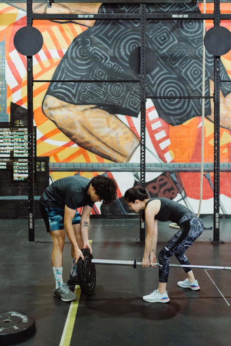 Man And Woman Exercise Together With Weights