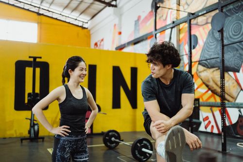 Free Two people in sportswear interacting in a vibrant gym environment, showing fitness and camaraderie. Stock Photo
