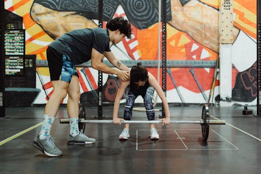 A coach instructs a young woman in proper barbell lifting technique at the gym.