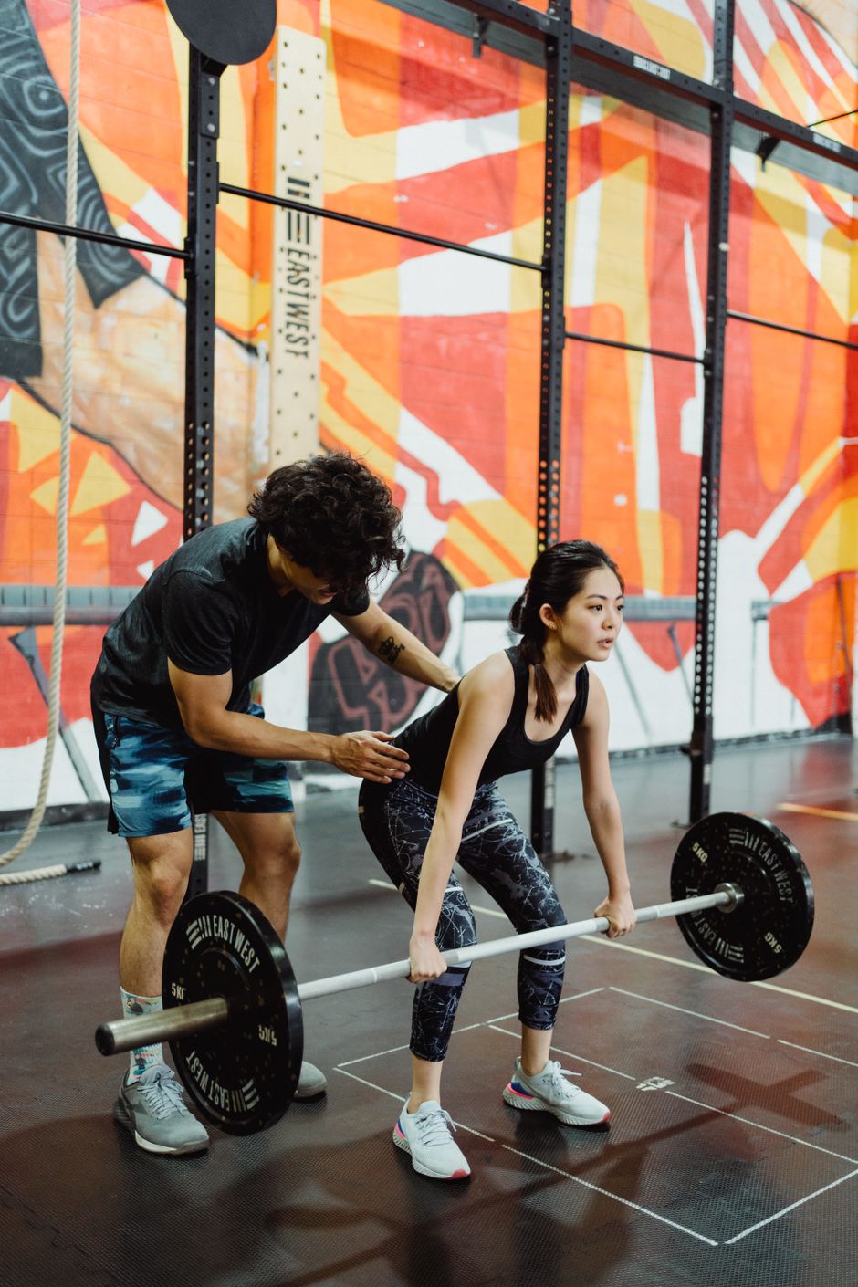 Coach guiding a member through a barbell lift during personal training