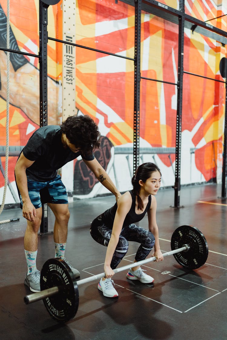 Trainer Helping Client Lifting Barbell