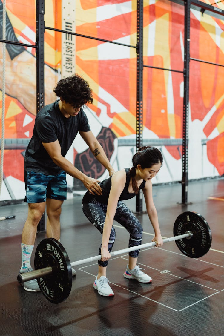 Photo Of A Man Helping A Woman with Weight Lifting