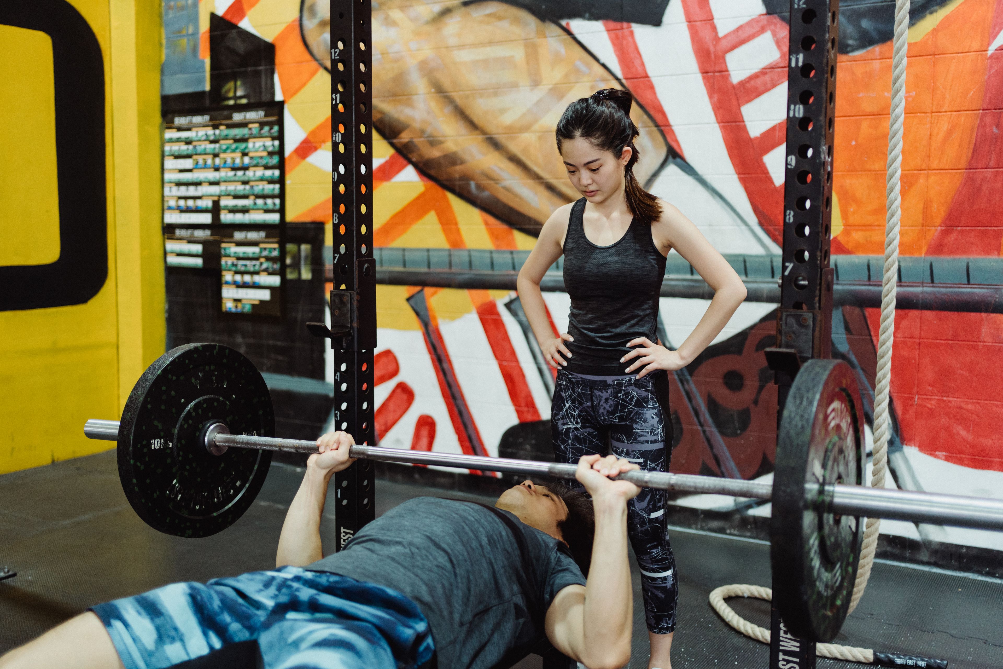 Man and woman doing bench press workout in gym, focusing on active lifestyle and fitness.