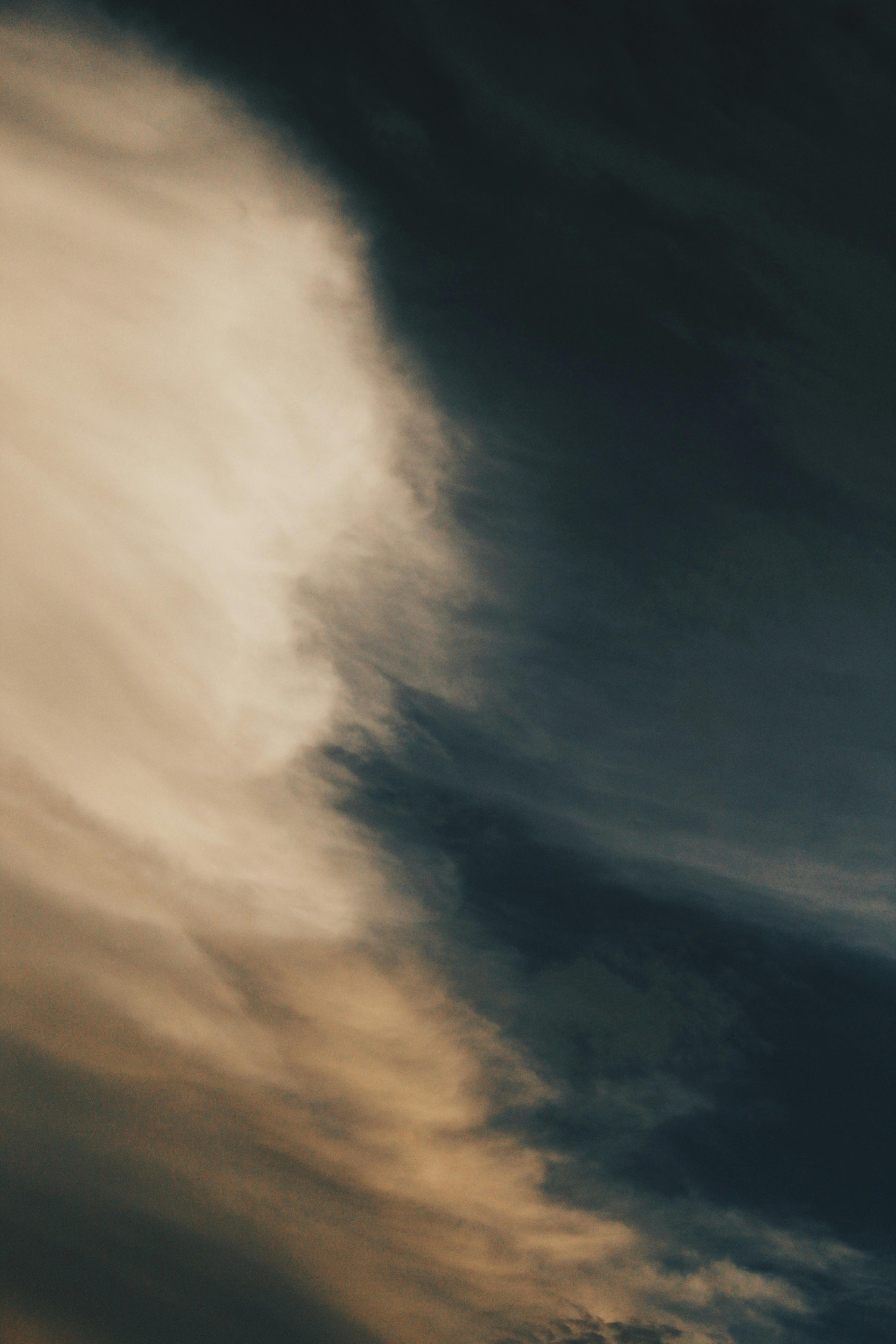 Captivating vertical shot of dynamic cloud formations against a dramatic sky, conveying a moody atmosphere.