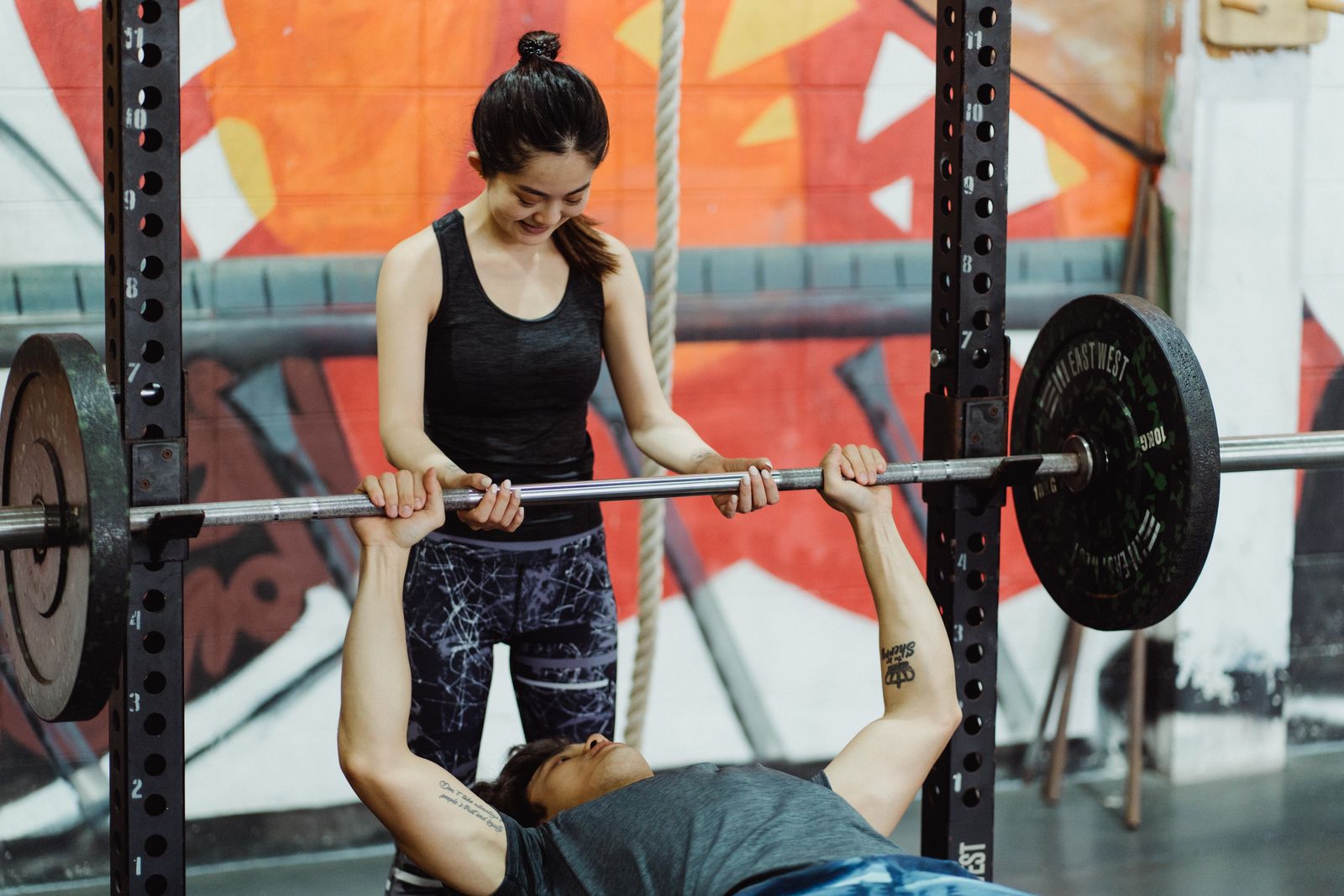 Athlete bench pressing with visible weight plates in a gym