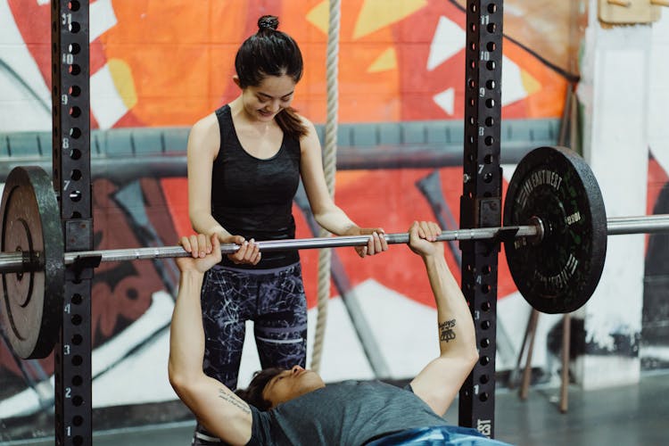 A Man Lifting A Barbell With Weight Plates 