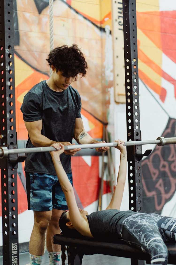 Photo Of A Man Helping A Woman Doing Bench Press