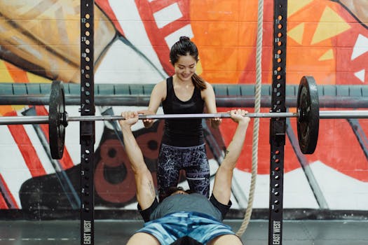 Asian couple engaged in fitness training at the gym, bench press exercise.