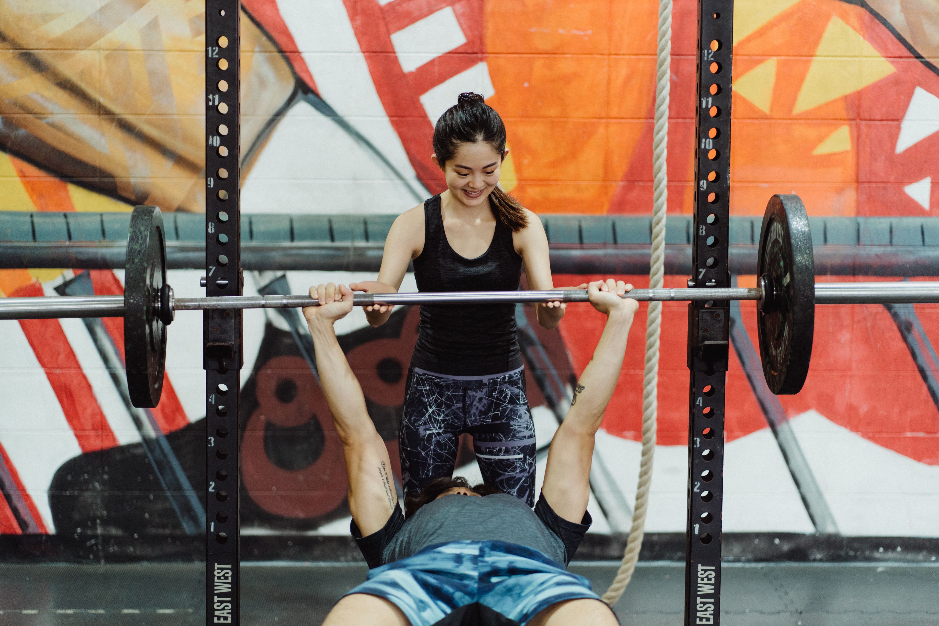 Asian couple engaged in fitness training at the gym, bench press exercise.