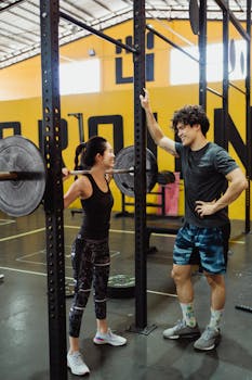 A young couple engaged in weightlifting exercises in a modern gym environment.