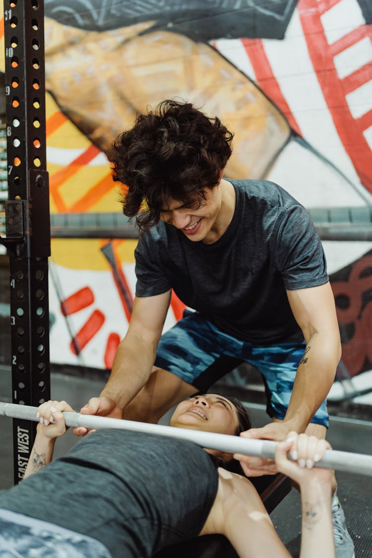 Photo Of A Man In A Gray Shirt Helping A Woman Doing A Bench Press