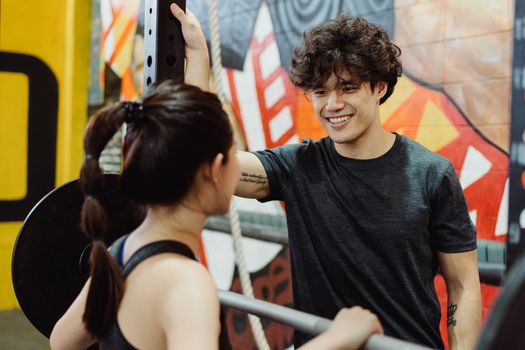 Happy young couple enjoying a workout at a vibrant indoor gym.