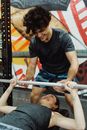 Man in a Gray Shirt Assisting a Woman Doing a Bench Press