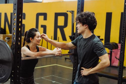 Free A man and woman enjoying a friendly moment during a gym workout, showcasing motivation. Stock Photo