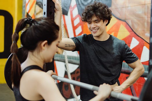 Smiling personal trainer coaching a woman lifting weights at the gym.