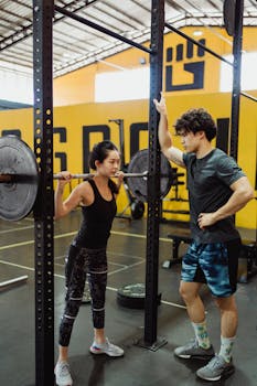 Asian couple working out in a gym, focusing on weightlifting and fitness training.