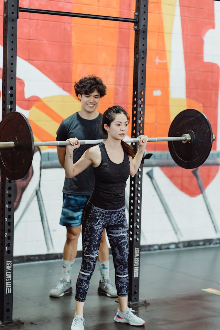 A Woman Carrying A Barbell With Weight Plates