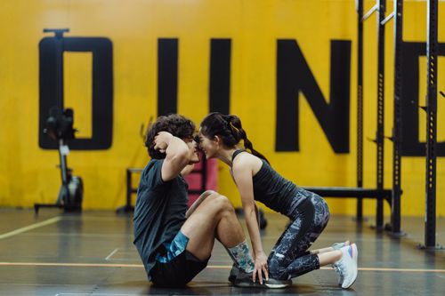 Free Smiling couple doing sit-ups face to face in a modern gym. Stock Photo