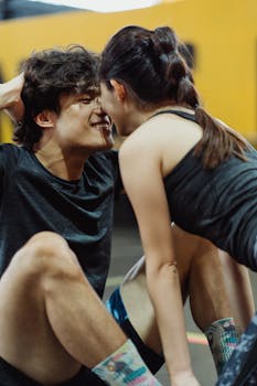 A couple shares a romantic moment during a sit-up workout indoors.