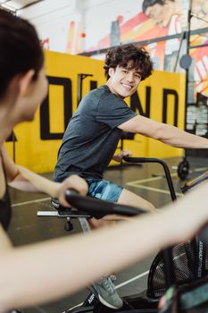 A young man smiles while exercising at a gym, promoting fitness and happiness.