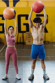 Asian couple in activewear working out with medicine balls indoors.
