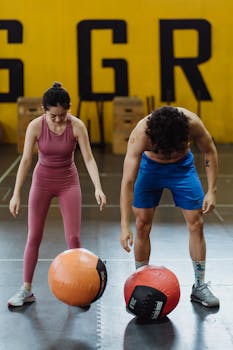 Two adults exercising indoors with medicine balls, focused on fitness and strength training.