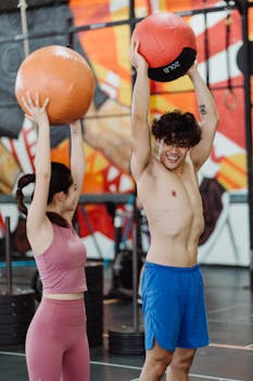 Fit couple working out together indoors with medicine balls, enhancing strength and fitness.