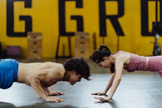 A fit Asian couple performing push-ups together in an indoor gym setting.