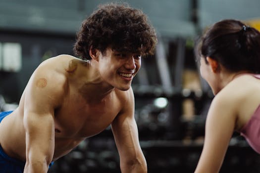 Smiling man working out shirtless in gym, engaged in conversation. Fitness and motivation.