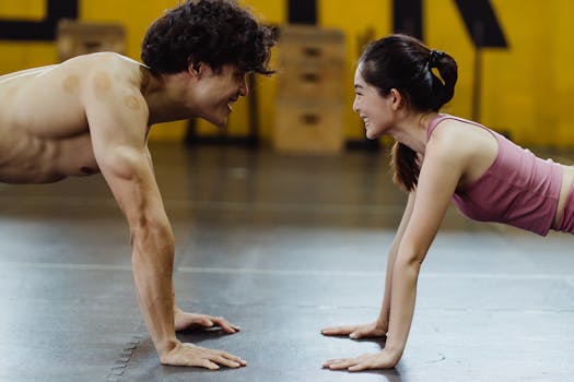A smiling couple engaged in a dynamic push-up workout session at a gym.