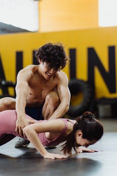 A young man and woman working out together in an indoor gym setting, focusing on teamwork and fitness.