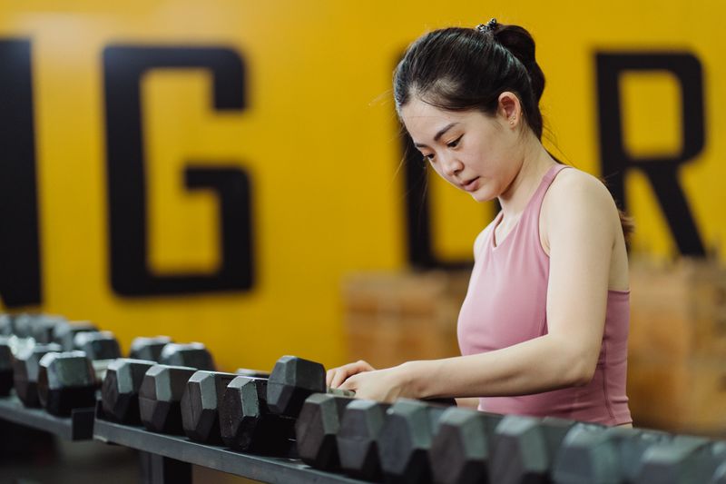 Mulher treinando com halteres para ganhar massa muscular e emagrecer