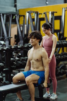 Man and woman in a gym engaged in a personal training session, focusing on fitness and health.