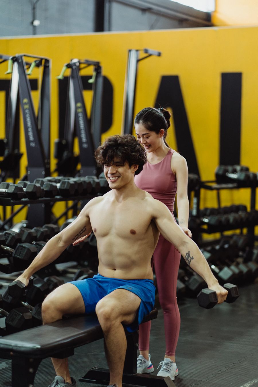 トレーナーが筋力トレーニングを補助している様子