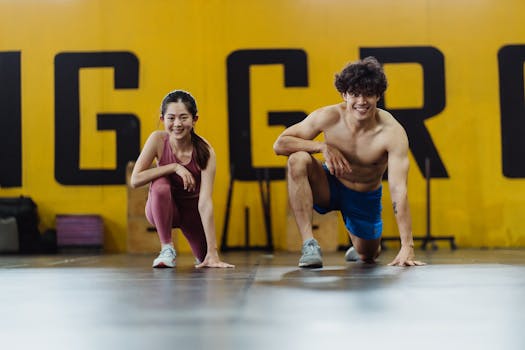 Male and female athletes stretching in a gym for strength and flexibility.