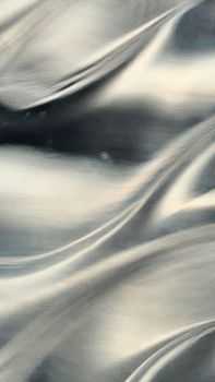 Close-up of abstract metallic silver fabric texture with flowing patterns.