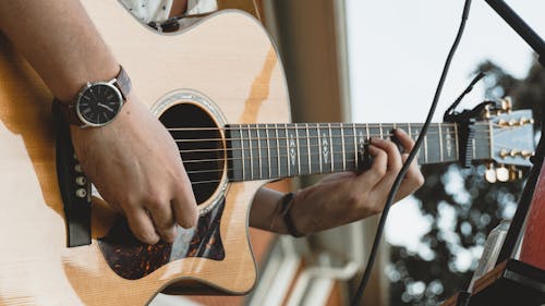 Person Playing Brown Acoustic Guitar