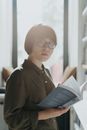 阳光明媚的图书馆里，一位戴眼镜的年轻女子正在看书