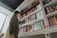 一名女子在舒适的室内图书馆中探索书架，寻求知识与休闲