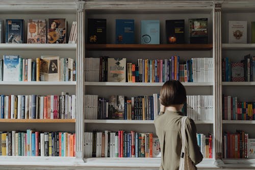 Vrouw In Beige Shirt Met Lange Mouwen Staan Voor Witte Houten Boekenplank